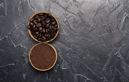 freshly roasted coffee beans and ground coffee in a wooden bowlの写真素材