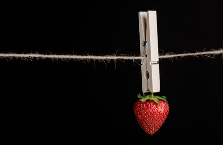 red strawberries on a dark background and clothespinの写真素材