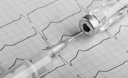 medical syringe with a needle and medicine on the background of a cardiogramの写真素材