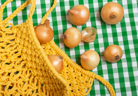 Fresh brown onion, agricultural produce, in knitted yellow bagの写真素材