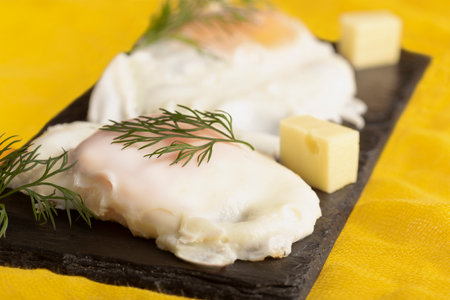 fried egg with herbs and cheese on a black stoneの写真素材