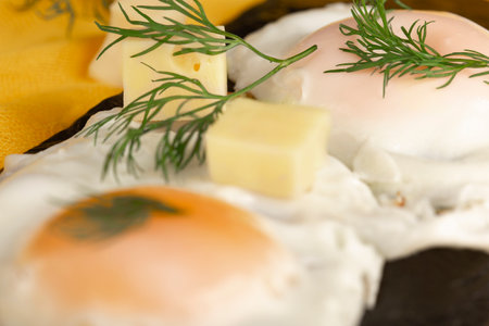 fried egg with herbs and cheese on a black stoneの写真素材