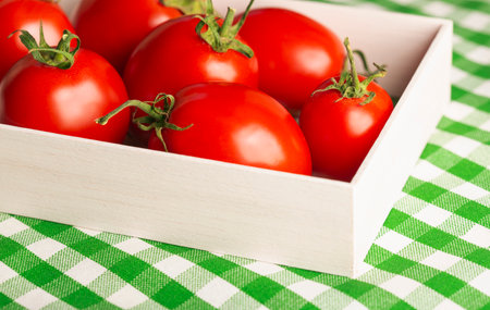 red tomatoes close up in a box on a green tableclothの写真素材