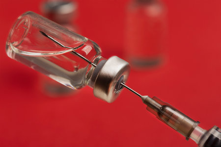 medical needle in ampoule with medicine on red backgroundの写真素材