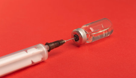 medical needle in ampoule with medicine on red backgroundの写真素材