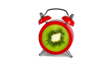 red alarm clock and kiwi in the center of the dial on a white backgroundの写真素材