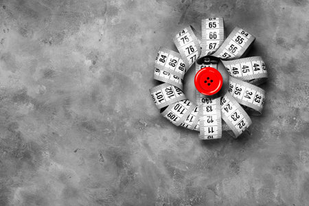 modern gray concrete background and measuring tape with red button top view