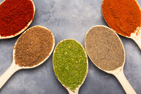 close up of spoons with spices of red and black pepper, dried herbs and paprika in spoons. Top view.の写真素材