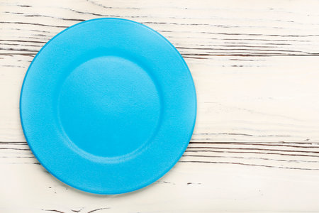 round empty blue plate on white wooden backgroundの写真素材