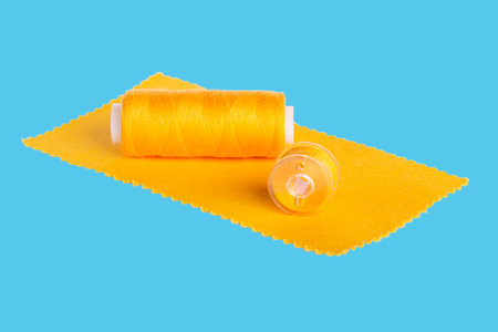 Yellow sewing threads and bobbin on a blue backgroundの写真素材