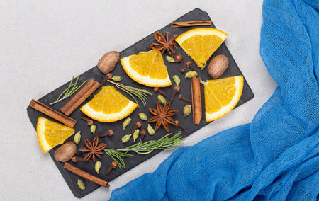 A spice set for mulled wine: cinnamon, orange, and cardamom. Light background and colored...
