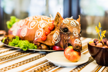 Decorated and roast suckling pig with an apple in his mouth on a white plate on banquetの写真素材