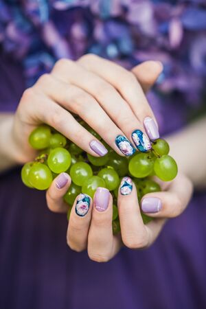 Beautiful hands with wonderful nails Holding a Bunch of Green Grapesの写真素材
