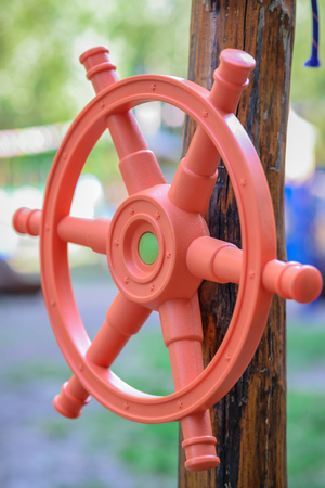 Red plastic children's handlebar of the ship a wooden girder on the playgroundの写真素材