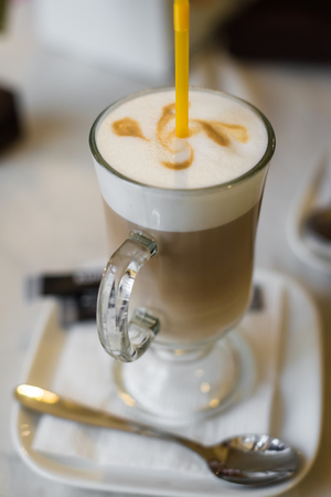 Coffee latte with a thick Crema and yellow straw in a restaurantの写真素材