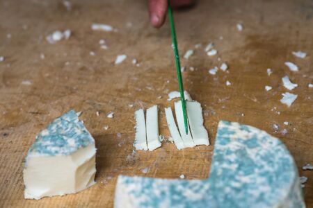 a pieces of cheese with blue mold is cut with a knifeの写真素材
