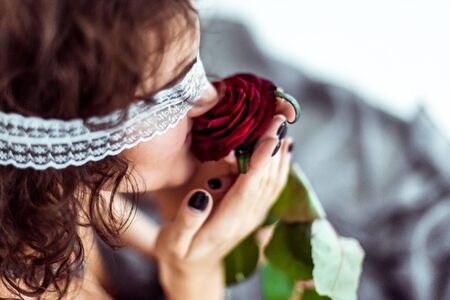Beautiful woman smells red roseの写真素材