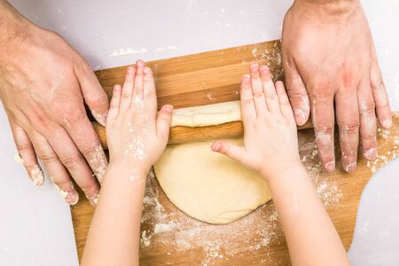 Children and dad hands rolled dough