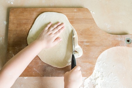 childrens hands cutting raw rolled doughの写真素材