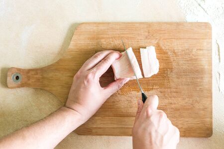 A mans hand cuts the pieces of fatの写真素材