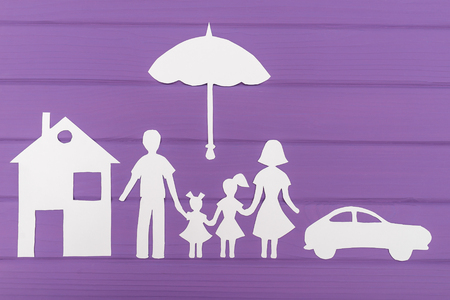 The silhouettes cut out of paper of man and woman with two girls under the umbrella, house and car nearの写真素材