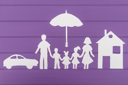 The silhouettes cut out of paper of man and woman with two girls and boy under the umbrella, house and car nearの写真素材