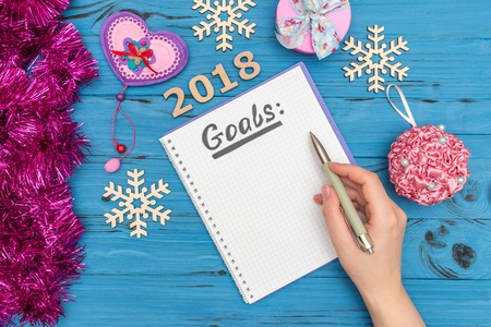 notebook with GOALS text and womans hand holding pen above with numbers 2018 and new year ornamentsの写真素材