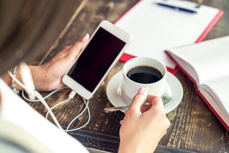 Young woman hand using phone black screen in cafe outdoor. Business concept. Mockup black screen