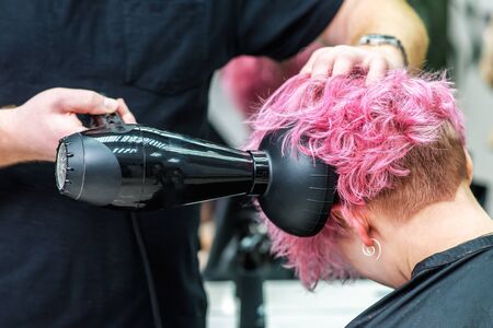 Professional hairdresser dries hair with a hairdryer in beauty hairdressersの写真素材
