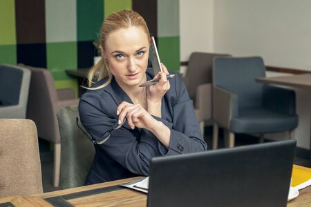 Successful young businesswoman with glasses talking on the smartphone at meeting room. Business conceptの写真素材
