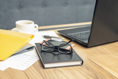 Side view glasses , smartphone, laptop, note book and pen on the wooden table. Selective focus office table. Business conceptの写真素材