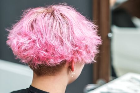 Beautiful hairstyle of young woman after dying hair and making highlights in beauty salon. Close up short pink hairdoの写真素材