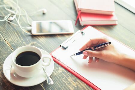 Closeup of a business woman hand is writing on a blank planner at cafe. Business concept. Copy space.の写真素材