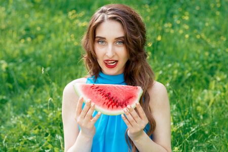 Attractive woman holds piece of watermelon while showing tongue out. Beautiful girl shows tongue out...