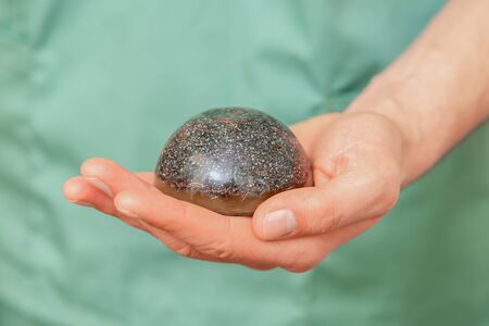 Male massage therapist holding hot spa stone, closeup.の写真素材