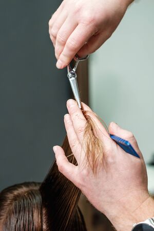 Hairdresser cutting woman's hair in beauty salon, close up.の写真素材
