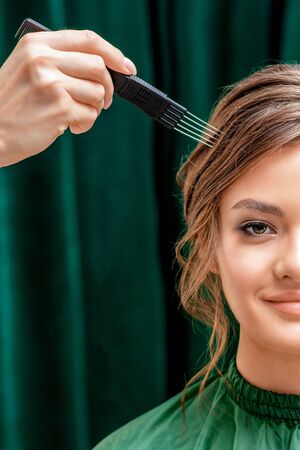 Hand of hair stylist combing hair of young woman, close up, concept beauty and hairstyle.