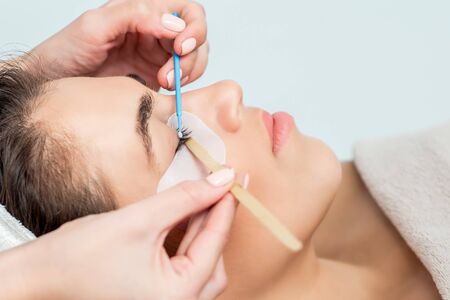 Cosmetologist's hand extends eyelashes with the help of a cotton bud.の写真素材