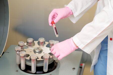 Doctor working with test tube of blood on centrifuge machine in medical clinic, analysis for coronavirus.の写真素材