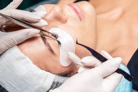 Procedure of eyelashes extension in salon for woman eye with long eyelashes during eyelash...