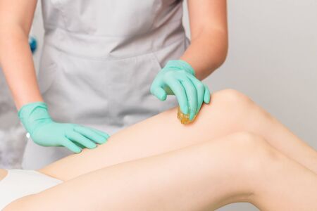 Beautician waxing female legs in spa center.の写真素材