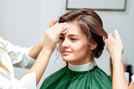 Smiling beautiful young woman receiving cleaning face skin by cotton pad in beauty salon. Skin care concept.の写真素材