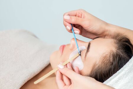 Beautiful young woman receiving eyelash extension procedure, close up.の写真素材