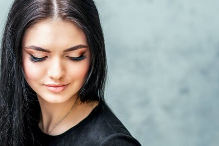 Long eyelashes and beautiful makeup of beautiful young woman on gray background with copy space.の写真素材