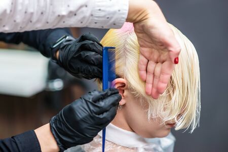 Hairdresser colors hair in pink colour close up.の写真素材