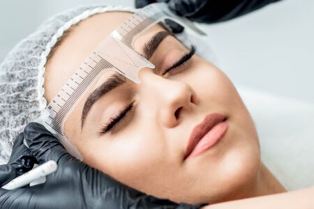 Markup with ruler on eyebrows of yong woman during permanent make up.