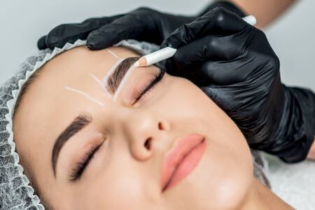 Markup with pencil on eyebrows of yong woman while permanent make up.の写真素材