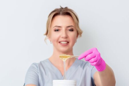 Beautician shows jar with wax for epilation on white background with copy space.の写真素材