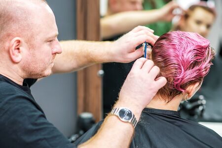 Hairdresser cuts wet pink hair pink hair of woman at hair salon. Haircut hair of woman.の写真素材