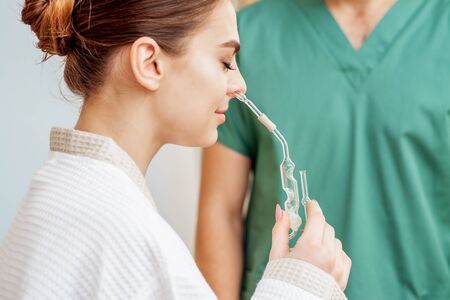 Woman receives nasal inhalation Maholda by essential oil in nose at spa.